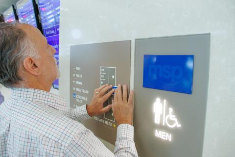 Man uses a tactile map to understand a restroom layout.